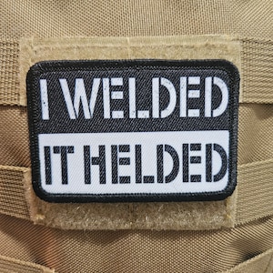 May include: A black and white patch with the text "I WELDED IT HELDED" on a tan background.