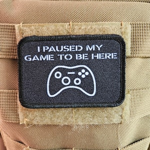 May include: Black patch with white text and a white video game controller icon. The text reads "I paused my game to be here."