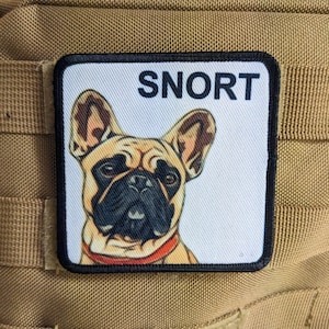 May include: A white patch with black stitching features a cartoon image of a French bulldog with a red collar. The text "SNORT" is printed in black at the top of the patch.