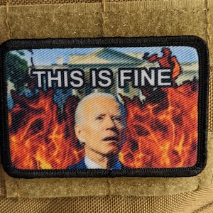 May include: A black and white patch featuring a cartoon image of a man wearing a blue shirt, set against a backdrop of flames. The text "THIS IS FINE" is printed in white on the patch.