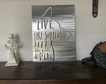Peut inclure: Une plaque en métal avec la silhouette d'un chien et le texte "Live like someone left the gate open".