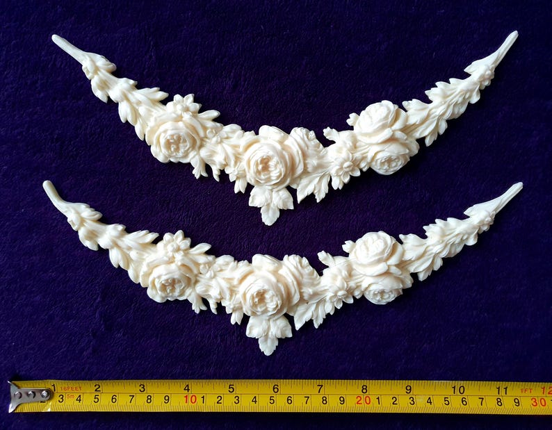 Pu&ograve; includere: Due applicazioni decorative floreali color crema. Ogni applicazione ha la forma di una ghirlanda curva, con rose e foglie dettagliate. Le applicazioni sono lunghe circa 30 cm, con un metro a nastro giallo in basso.