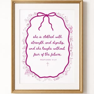 Può includere: Stampa incorniciata con bordo dorato. L'opera presenta uno sfondo bianco con una cornice ovale magenta. All'interno della cornice, il testo recita: «è rivestita di forza e dignità, e ride senza paura del futuro». PROVERBI 31:25.