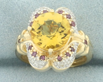 May include: A gold ring with a large yellow gemstone surrounded by smaller pink gemstones and white diamonds.
