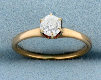 Puede incluir: Un anillo de banda de oro con un solo diamante redondo y claro engastado en un engaste de cuatro garras.