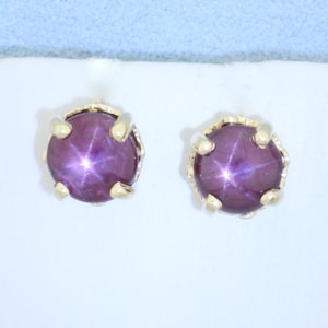 May include: A pair of gold star ruby earrings with a six-prong setting.