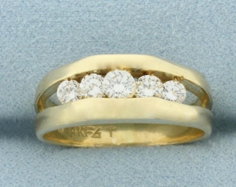 May include: A gold ring with five round, clear diamonds set in a channel style. The ring has a two-tone design, with a polished gold band and a brushed gold setting for the diamonds. The ring is marked with "14K F&T".