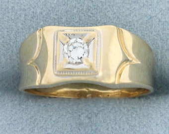 May include: A gold ring with a square setting and a single round diamond in the center.