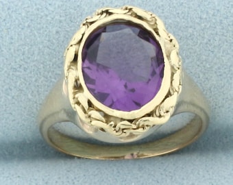 May include: A gold ring with an oval-shaped amethyst gemstone set in a detailed, ornate design.