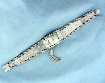 May include: A silver bracelet with a diamond-shaped centerpiece and a tassel. The bracelet is made of a rope-like chain with small stars engraved on each link.