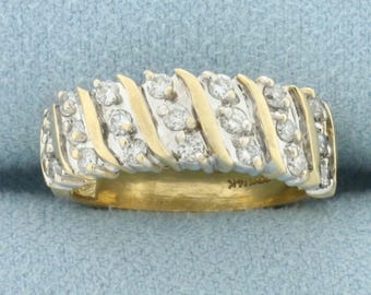 Puede incluir: Un anillo de banda de oro con un diseño engastado en diamantes. Los diamantes están engastados en un patrón de espiral, creando un aspecto único y elegante.