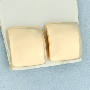 May include: A pair of gold square-shaped earrings. The earrings are smooth and have a polished finish.