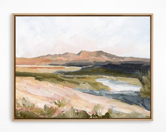 May include: An abstract landscape painting in a natural wood frame. The artwork features a mountain range in shades of brown and gray, with a foreground of green and beige fields. A body of water is visible in the center, and the sky is a soft white.