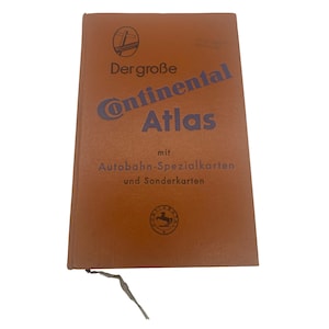 May include: A vintage brown "Continental Atlas" book with blue lettering and German text. The cover features a logo and the title "Dergroße Continental Atlas" with additional text below. A small, torn piece of paper is attached.