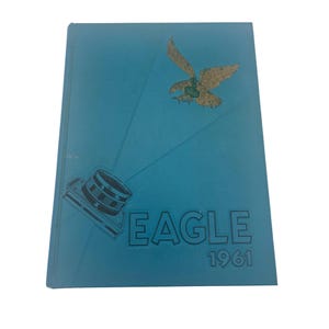 May include: A teal-colored yearbook with a gold eagle graphic and a camera illustration. The word "EAGLE" is printed in large letters, with "1961" below. The cover has a textured appearance.