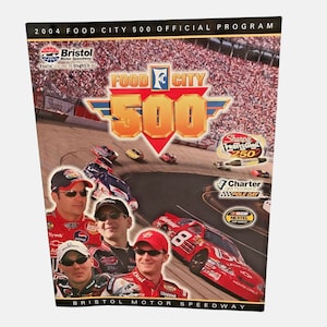 Può includere: Una guida al programma per la gara Food City 500 del 2004 al Bristol Motor Speedway. La copertina presenta un logo rosso, bianco e giallo per la gara, insieme a foto di quattro piloti di corse.
