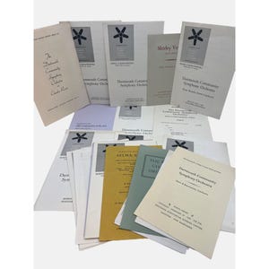 May include: A stack of white, yellow, and blue paper flyers with the text "Dartmouth Community Symphony Orchestra" printed on them. The flyers are for various concerts and events.