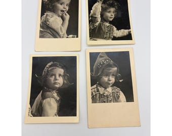 May include: Four vintage black and white photographs featuring a young child wearing a decorative vest and a pointed hat. The child is captured in various poses, including looking upward and touching their face, with a light border around each.