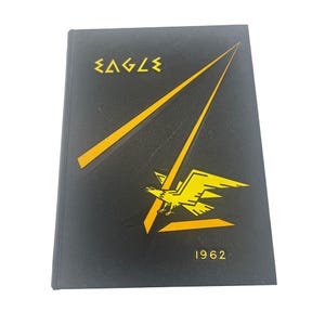May include: Black hardcover yearbook with the word "EAGLE" in yellow stylized text at the top. A yellow eagle graphic and the year "1962" are also featured. The cover has a textured appearance.