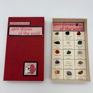 Può includere: Un set Scott Study Collection Gem Stones of the World composto da una scatola rossa con etichetta rosa e un vassoio espositore aperto abbinato. Il vassoio contiene quindici campioni di minerali etichettati, tra cui giada, diaspro, ametista e varie agate.