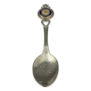 Puede incluir: Una cuchara de recuerdo vintage con acabado plateado. La cuchara presenta un emblema con el texto "GREAT SMOKY MOUNTAINS" y un recorte en forma de corazón. El cuenco de la cuchara tiene un contorno grabado de Carolina del Norte con el texto "RALEIGH".