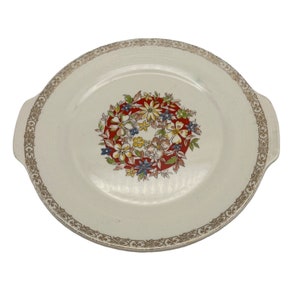 May include: A white ceramic serving plate with two handles. The plate has a gold rim and a floral design in the center. The flowers are red, yellow, blue, and green.