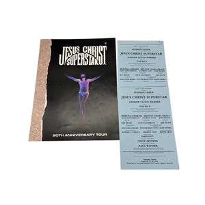 May include: A promotional item for the musical "Jesus Christ Superstar" featuring a program and a brochure. The brochure has a black background with the musical's title and a figure. The program is light blue with cast and crew credits.