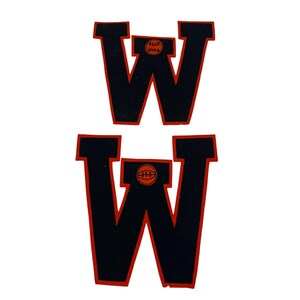 May include: Two black felt letters, W, with red outlines and a small orange baseball graphic in the center of each letter.