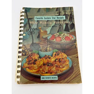 May include: A spiral-bound cookbook titled Favorite Eastern Star Recipes Olde Family Favorites Including Menus 2000 Favorite Recipes. The cover features a color photograph of cooked chicken pieces on a plate and a bowl of food in a kitchen setting.
