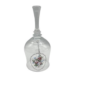 Peut inclure: Une cloche en verre transparent avec une chaîne argentée et un motif floral peint. Le motif floral présente des roses roses et des fleurs bleues.
