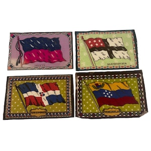 May include: Four rectangular decorative pieces featuring flags of different countries. The flags include Haiti, South African Republic, San Domingo, and Venezuela. Each flag is displayed on a patterned background with a decorative border. The flags are in various colors.
