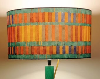 Drum lampshade in mosaic chintz in warm colors on an emerald green background