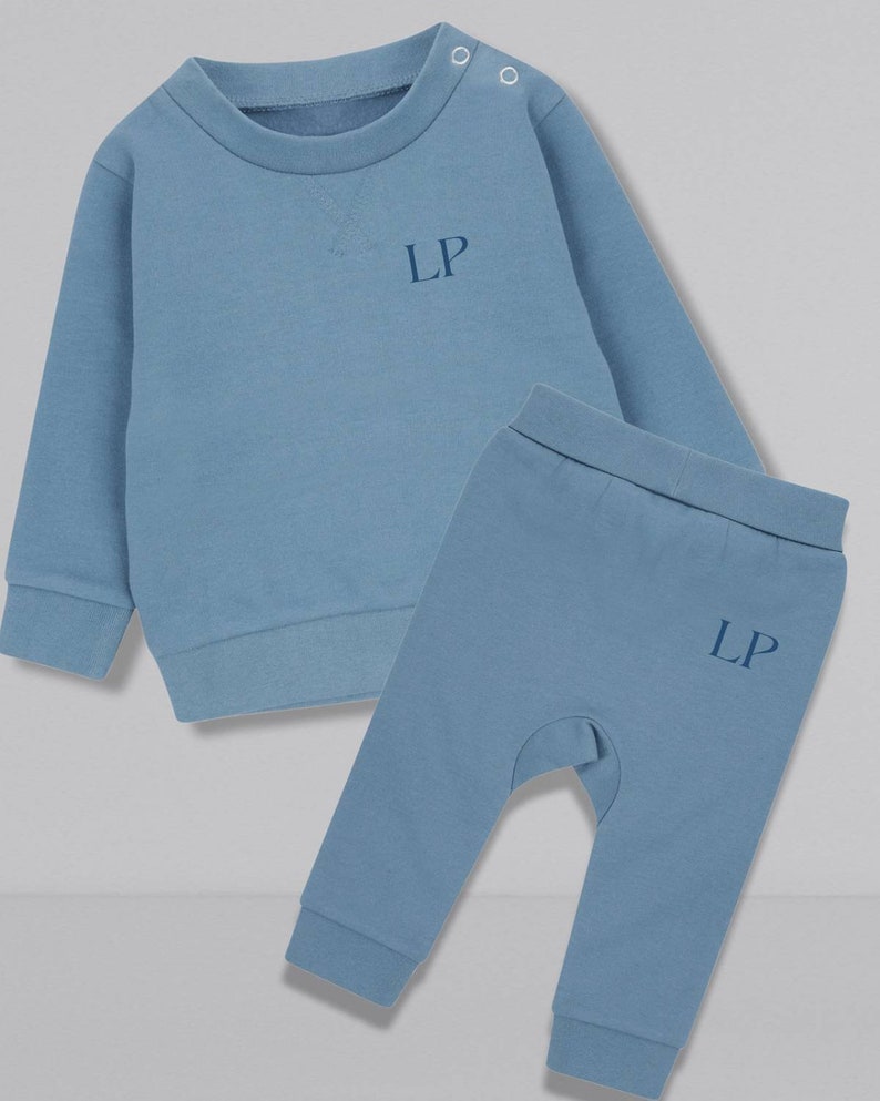 May include: A blue baby sweatshirt and matching pants set with the initials "LP" embroidered on both pieces.