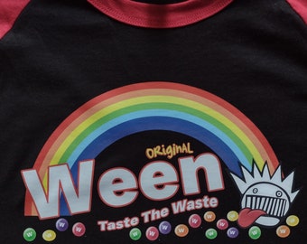 May include: Black and red baseball tee shirt with a rainbow arc and the words "Original Ween Taste The Waste" in white letters. The graphic also includes a cartoon character with a tongue sticking out and a row of colorful "W"s.