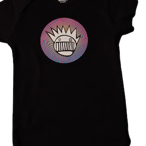 Puede incluir: Body de bebé negro con un gráfico circular en la parte delantera. El gráfico presenta una cara de dibujos animados blanca con una corona y un fondo arremolinado colorido en tonos rosa, azul y amarillo. El body tiene la marca "Gerber".