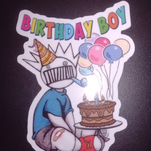 May include: A cartoon birthday boy wearing a party hat and holding a cake with candles. The boy is wearing a blue shirt, grey shorts, and red socks. There are colorful balloons in the background. The text "BIRTHDAY BOY" is written in rainbow colors at the top of the image.