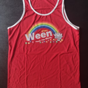 May include: Red sleeveless tank top with a white trim around the neck and armholes. The front of the shirt features a rainbow, the word "Ween" in white letters, and the text "Original Taste The Waste" in white letters. There are also small colorful candies around the text.
