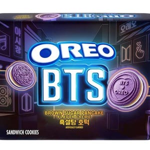 Puede incluir: Un paquete rectangular de galletas sándwich Oreo BTS con un fondo morado oscuro y gráficos de estilo neón. El frente muestra los logotipos de Oreo y BTS, el texto Brown Sugar Pancake Flavor Creme y dos galletas moradas con corazones.