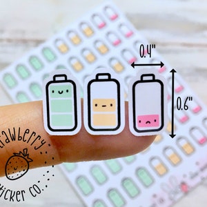 May include: A sheet of 0.4 inch by 0.6 inch stickers featuring three different battery designs. The batteries are green, yellow, and white with a pink accent. Each battery has a cute face. The stickers are labeled "Strawberry Sticker Co."
