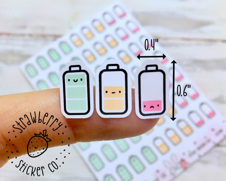 May include: A sheet of 0.4 inch by 0.6 inch stickers featuring three different battery designs. The batteries are green, yellow, and white with a pink accent. Each battery has a cute face. The stickers are labeled "Strawberry Sticker Co."