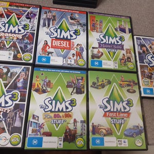 May include: A collection of The Sims 3 video game expansion packs and stuff packs. The game cases feature colorful graphics and text, including "Seasons," "Diesel," "Master Suite Stuff," "Ambitions," "University Life," "70s 80s 90s Stuff," and "Fast Lane Stuff."