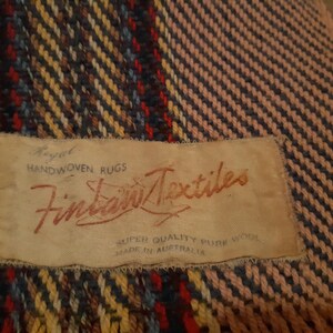 Peut inclure: Textile tiss&eacute; avec une &eacute;tiquette indiquant "Royal Handwoven Rugs Fintan Textiles Super Quality Pure Wool Made in Australia". Le textile pr&eacute;sente un motif de fils rouges, bleus, jaunes et bruns.