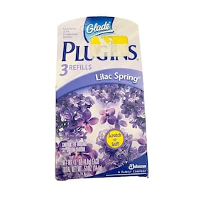 May include: A Glade Plugins air freshener refill box with a lilac spring scent. The box features a purple floral design and the words "Lilac Spring." It contains three refills, with a net weight of 1.7 oz (4.8g) each.