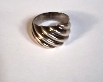May include: A silver-toned ring featuring a continuous, twisted, or ribbed design that wraps around the entire band. The metal surface has a polished, reflective finish with deep grooves creating a dimensional, spiraling pattern throughout the band.