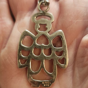 Puede incluir: Colgante de &aacute;ngel plateado con halo y alas caladas. El colgante est&aacute; marcado "MEXICO 925". Las alas del &aacute;ngel tienen recortes en forma de coraz&oacute;n. En la parte superior hay un peque&ntilde;o lazo.