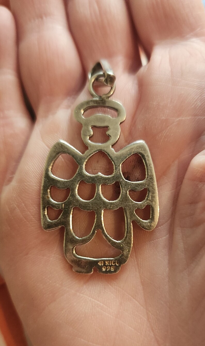 Puede incluir: Colgante de &aacute;ngel plateado con halo y alas caladas. El colgante est&aacute; marcado "MEXICO 925". Las alas del &aacute;ngel tienen recortes en forma de coraz&oacute;n. En la parte superior hay un peque&ntilde;o lazo.