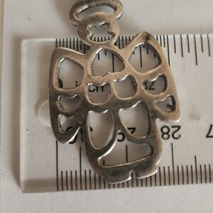 Puede incluir: Colgante de &aacute;ngel plateado con halo y dise&ntilde;o calado. El colgante mide aproximadamente 4 cm de altura y est&aacute; suspendido de un peque&ntilde;o lazo. Las alas y el cuerpo del &aacute;ngel presentan espacios abiertos.