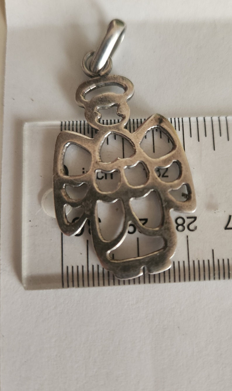 Puede incluir: Colgante de &aacute;ngel plateado con halo y dise&ntilde;o calado. El colgante mide aproximadamente 4 cm de altura y est&aacute; suspendido de un peque&ntilde;o lazo. Las alas y el cuerpo del &aacute;ngel presentan espacios abiertos.