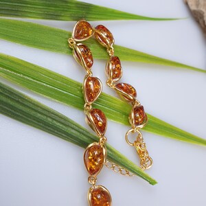 May include: A gold bracelet with amber teardrop-shaped stones. The bracelet has a lobster clasp closure.