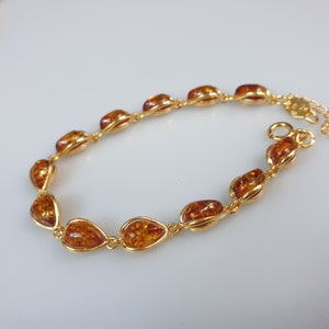 May include: A gold bracelet with amber teardrop-shaped stones. The bracelet has a delicate chain and a secure clasp.